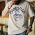 Person wearing a white t-shirt with blue graphic design and text.